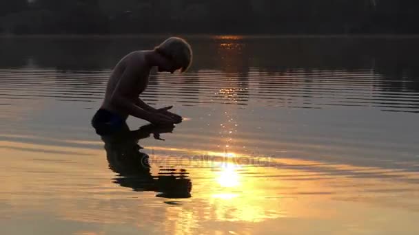 Arty Man ridică apa râului în palme și o lasă să cadă înapoi la apusul soarelui — Videoclip de stoc