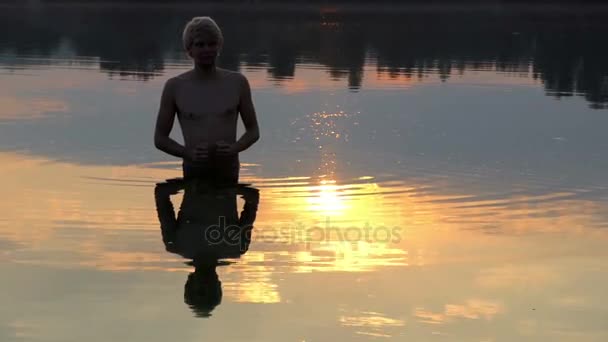 Αντανάκλαση του ένας άνθρωπος προσεύχεται παρατηρείται στα νερά της λίμνης σε ένα υπέροχο ηλιοβασίλεμα — Αρχείο Βίντεο