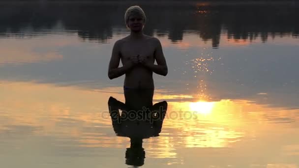 Weerspiegeling van een Man bidden is gezien in de wateren van Lake bij een prachtige zonsondergang — Stockvideo