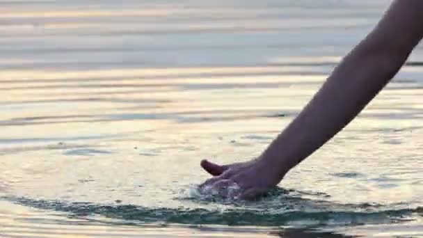 Mano masculina hace un círculo alrededor de sí mismo en el agua del lago al atardecer en Slo-Mo — Vídeos de Stock