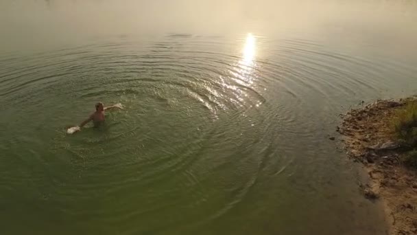 Aérea - Un joven gira las manos en un lago al atardecer — Vídeos de Stock