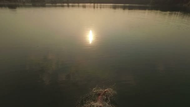 Foto aérea de un lago con un sendero soleado y un hombre nadando a lo largo de él — Vídeos de Stock