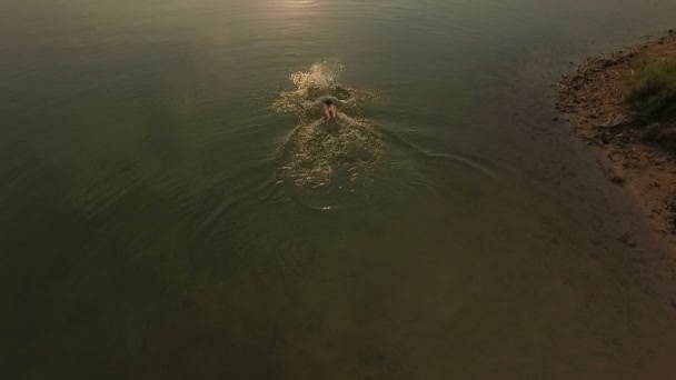 Foto aérea de un lago con un sendero soleado y un hombre nadando mariposa — Vídeos de Stock