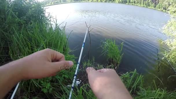 Two hands show thumb up gestures near fishing spinnings on a lake — Stock Video