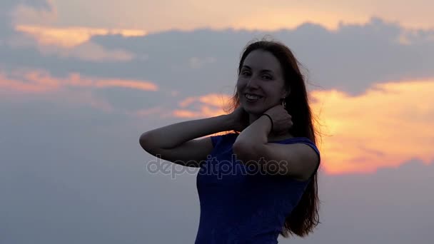 Uma mulher sorrindo frolics e levanta seu cabelo longo solto em slo-mo — Vídeo de Stock