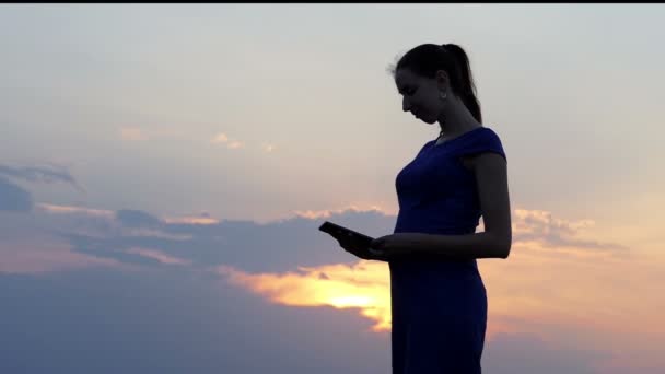 Вагітна жінка телефонує своєму другові за допомогою смартфона на заході сонця в шлю-мо — стокове відео