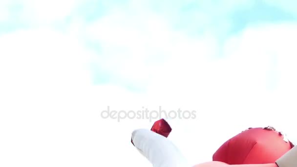 En stor röd gummi figurera full av luft gungar i ett blåsigt väder — Stockvideo