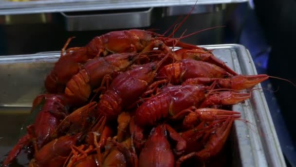 Decenas de cangrejos rojos yacen en bandejas metálicas con espigas de maíz al aire libre — Vídeo de stock