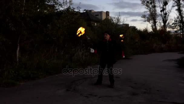 Een magische Man jongleert twee verlichte fakkels in de avond buiten in Slo-Mo — Stockvideo