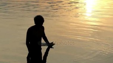 Sanat konusunda hava atan adam hamle nehir suyu onun avucunda bir güneşli yolu günbatımı ile