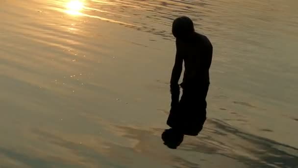 Arty Man kijkt Raises rivierwater in handenvol. het valt naar beneden in stromen bij zonsondergang — Stockvideo