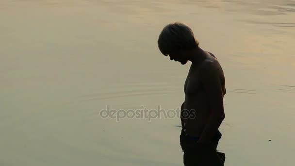 Férfi áll, folyó víz. Ujjai séta a felszínen a naplemente — Stock videók