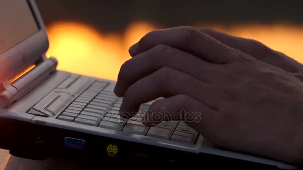 夜の川の銀行に屋外 pc キーボードでタイプする男性の指 — ストック動画