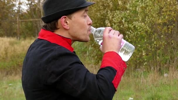 Young Man in a Black Hat Stands in a Forest And Drinks Some Liquid in Slo-Mo — Stock Video