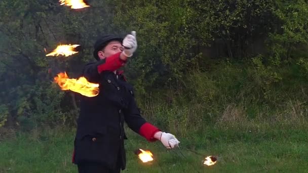 Młody kuglarz skręca dwa metalowe fanów z płomień wokół siebie w Slo-mo to magia — Wideo stockowe