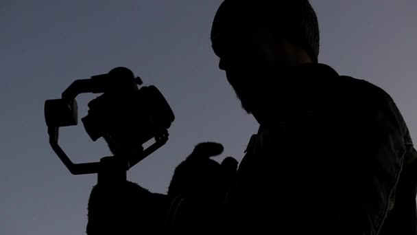 Un uomo della macchina fotografica spara un uomo di fuoco e gira la sua Steadicam in profondità di notte in Slo-Mo — Video Stock