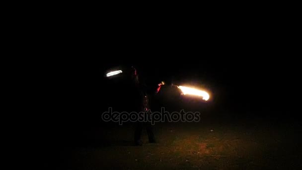 Młody człowiek zamienia zapalonymi pochodniami wokół siebie w nocy na zewnątrz w Slo-Mo. — Wideo stockowe