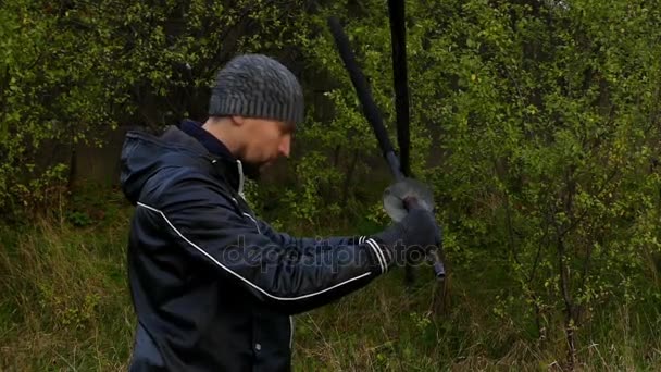 Junger Kämpfer dreht als Profi im Slo-Modus zwei orientalische schwarze Schlagstöcke im Wald — Stockvideo