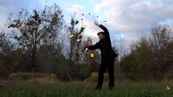 Brand Juggler wendingen twee verlichte Fans rond zichzelf buiten in Slo-Mo in de herfst. — Stockvideo