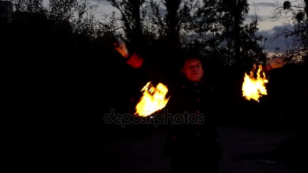 Malabarista gira dos palos de luz con bolas de fuego en la noche al aire libre en Sutumn — Vídeos de Stock