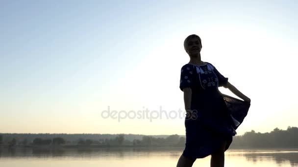 Uma mulher agradável flutters seu vestido popular no por do sol em 4k — Vídeo de Stock