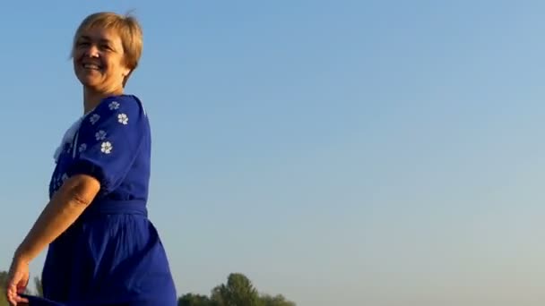 Een lachende vrouw fladdert haar jurk in de zomer — Stockvideo