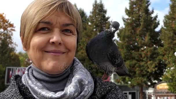 Een gelukkige vrouw staat met een duif op haar schouder in slo-mo — Stockvideo