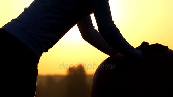 Sportive woman stands on knees and roll a ball at sunset — Stock Video