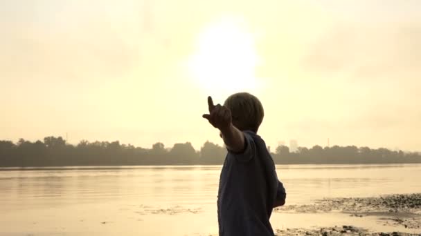 Joven lanza su mano hacia adelante, disfruta de la vida, en una orilla del río en Slo-Mo — Vídeo de stock