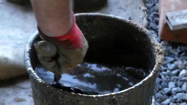 L'uomo mescola cemento e acqua in un secchio per ottenere una malta grigia — Video Stock