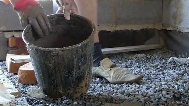 Un homme verse de la solutuine de mortier sur du gravier pour obtenir un sol en béton — Video