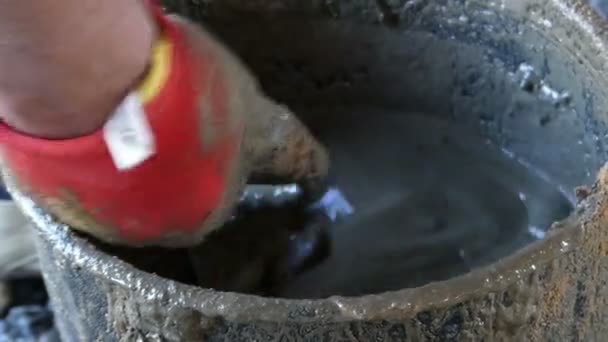 Μια αρσενική χέρι σε γάντι αναμιγνύει το τσιμέντο και νερό για να πάρει κονίαμα — Αρχείο Βίντεο