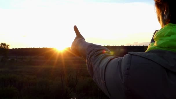 Una mujer mira el atardecer y muestra dos gestos de pulgar hacia arriba en slo-mo — Vídeo de stock