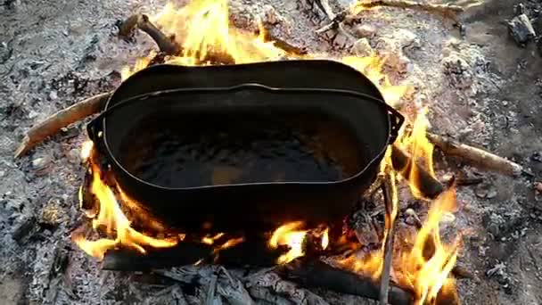 Il calderone ovale sta in un falò. Fa bollire l'acqua al tramonto al rallentatore — Video Stock