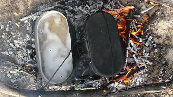 Dos calderos metálicos con agua hirviendo sobre ceniza de fuego en verano — Vídeo de stock