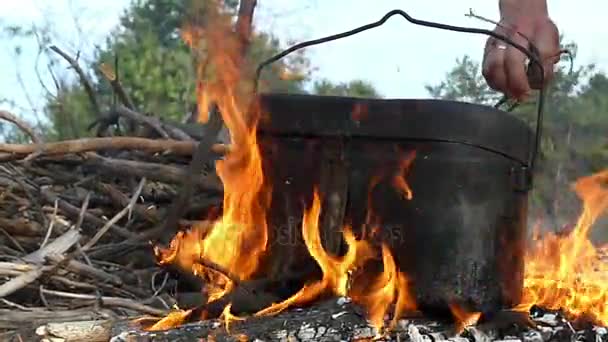 Mão masculina coloca mato sob o caldeirão em um fogo em slo-mo — Vídeo de Stock