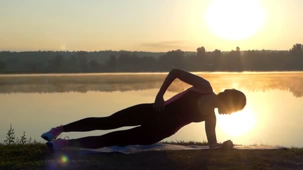 Femme mince repose sur sa hanche et le coude et les trains au coucher du soleil — Video