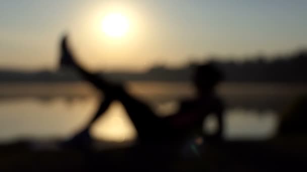 Soft view of a woman training herself on a lake bank — Stock Video