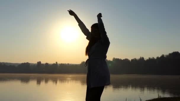 Happy young woman dances on a lake bank at sunset — Stock Video