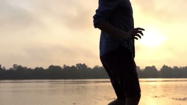 Hombre feliz baila en una impresionante orilla del río en una espléndida puesta de sol en Slo-Mo — Vídeos de Stock