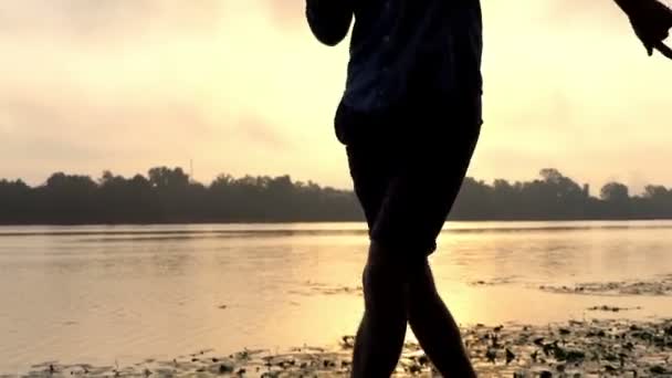 Emocional hombre baila en una impresionante orilla del río en una espléndida puesta de sol — Vídeos de Stock