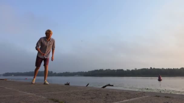 Jonge Man in korte broek loopt snel langs de rivieroever Dnipro bij zonsondergang in Slo-Mo — Stockvideo