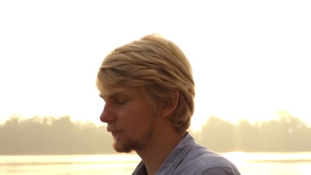 Skäggig Man står och sätter hår i ordning på Dnipro vid solnedgången i Slo-Mo — Stockvideo