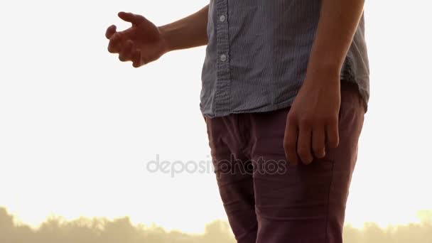 Homem barbudo sustenta e coloca o cabelo em ordem na margem do rio ao pôr do sol em Slo-Mo — Vídeo de Stock