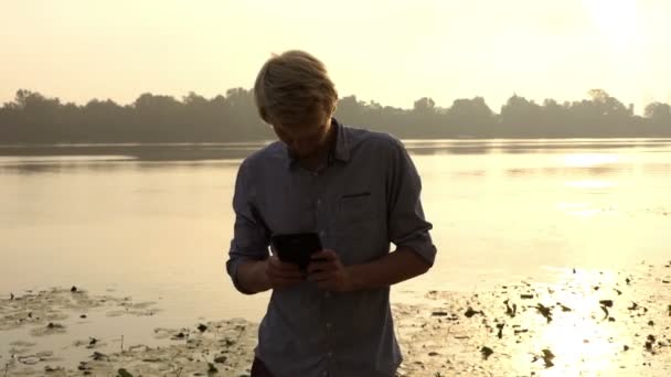 Homem barbudo olha para seu smartphone e sorri ao ar livre para o Dnipro — Vídeo de Stock