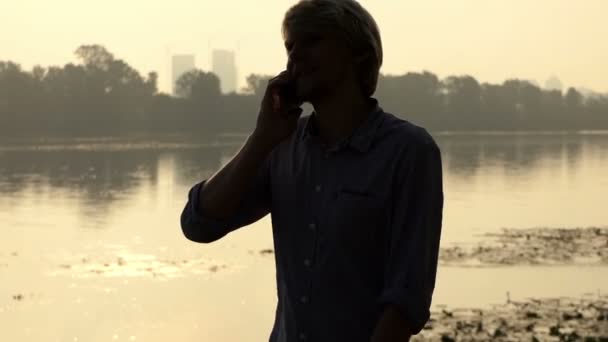 大胡子男子站起来, 掏出他的手机, 在日落时开始呼唤斯洛伐克 — 图库视频影像