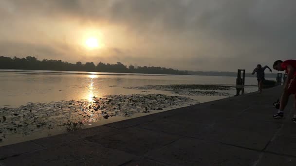 Jovem atleta corre rápido ao longo da margem do rio Dnipro concreto ao pôr do sol em Slo-Mo — Vídeo de Stock