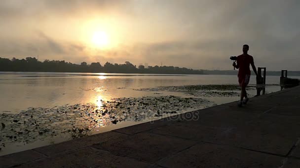 Genç kamera adam mutlu Slo-mo gün batımında Dnipro nehir kıyısı yürür — Stok video