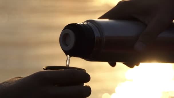 Muž rukou nalít vodu z láhve do šálku na břehu při západu slunce v Slo-Mo — Stock video