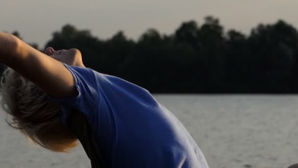 Yawning Man faz um exercício relaxante em uma cadeira dobrável ao pôr do sol em Slo-Mo — Vídeo de Stock